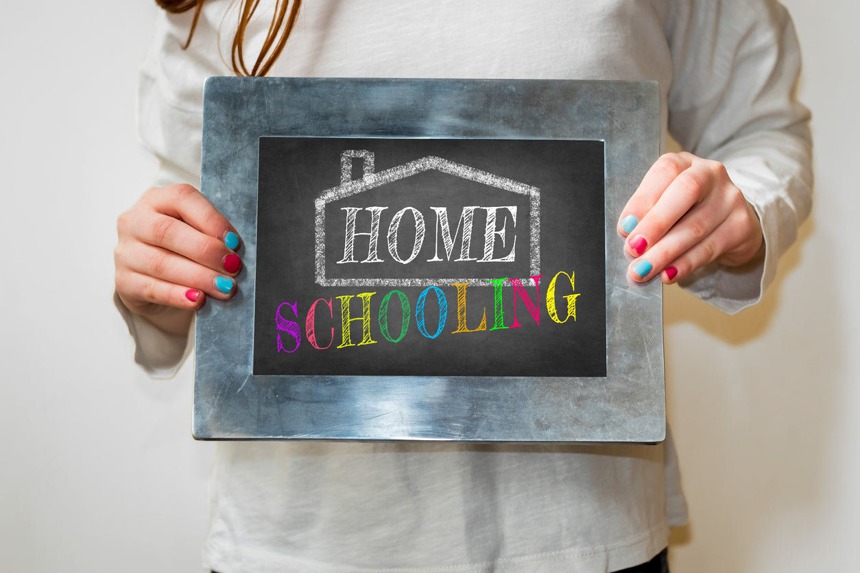 Child holding up a blackboard with home schooling written on it