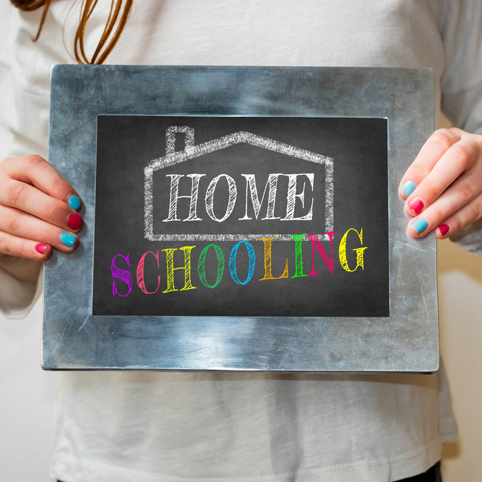 Child holding up a blackboard with home schooling written on it