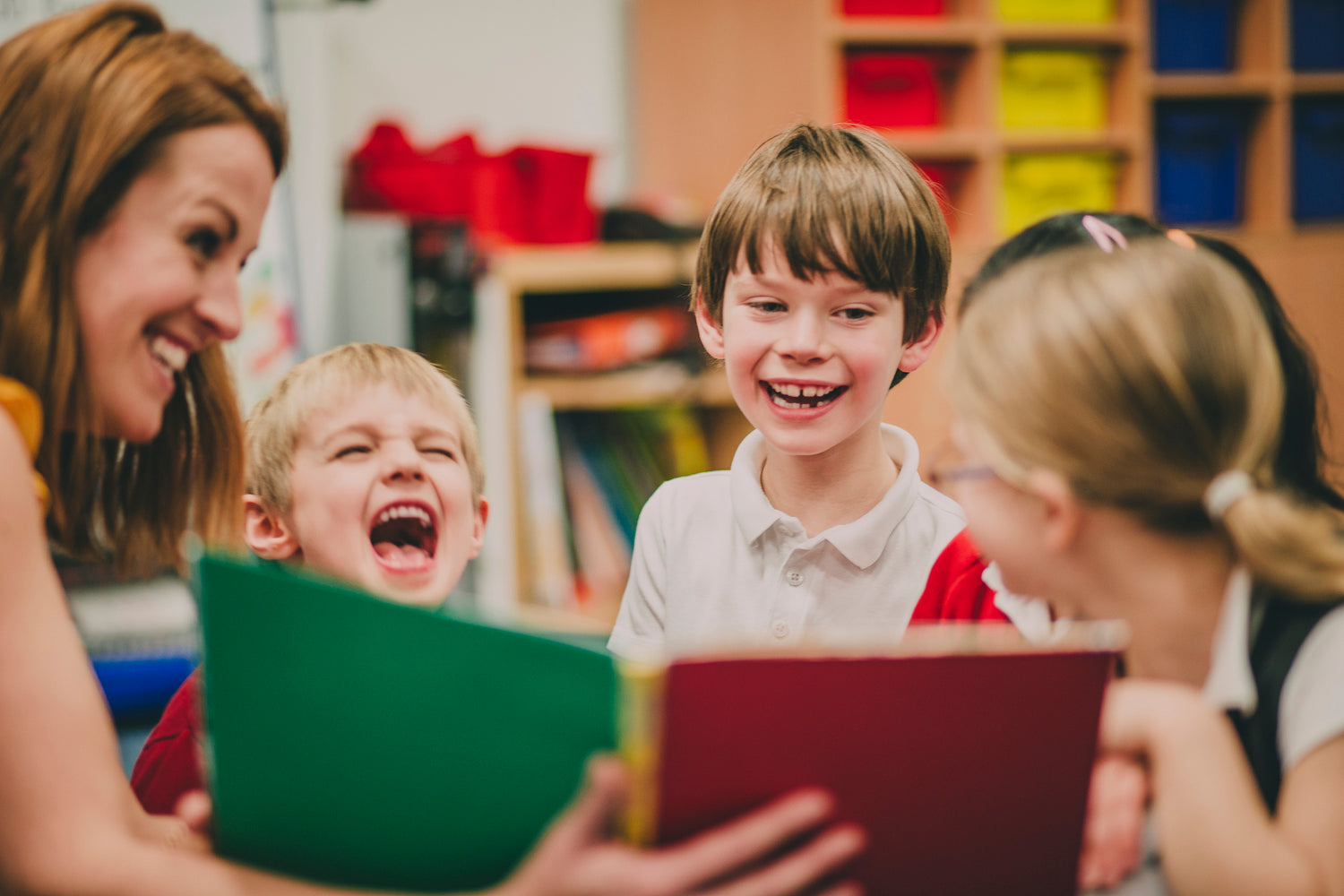 Teacher sharing a book with laughing children