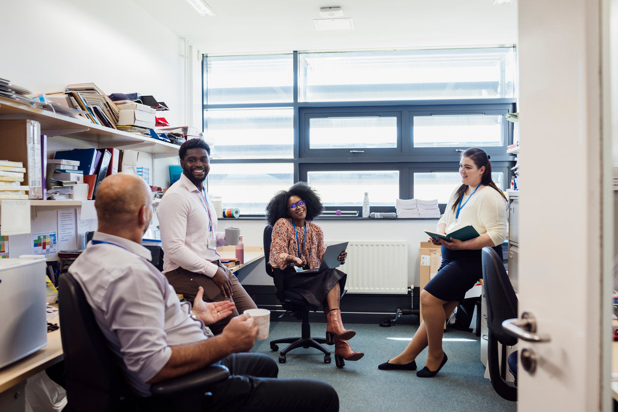 Four people in an office discussing around a table.
